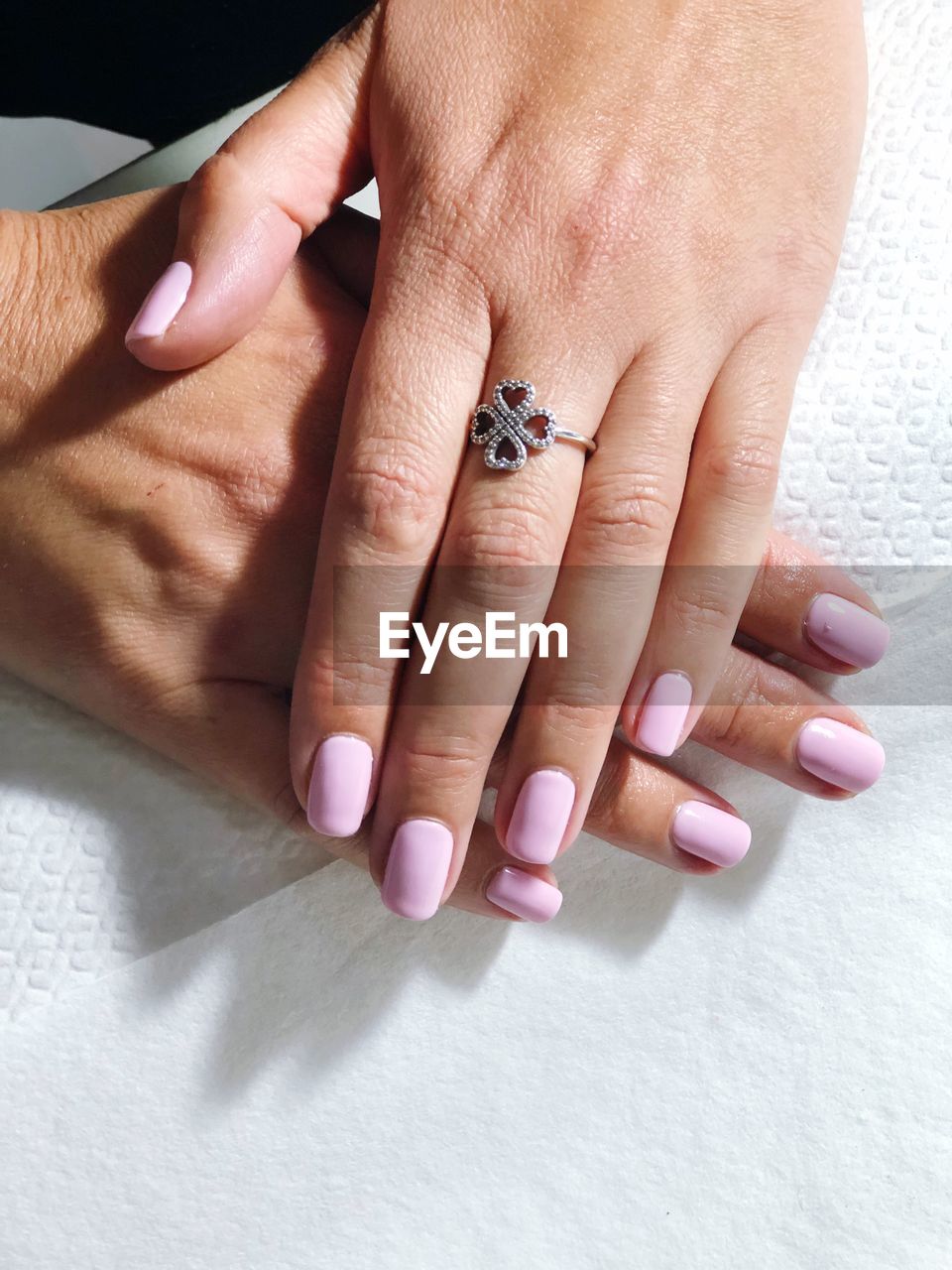 Cropped image of woman with painted fingernails wearing ring on table