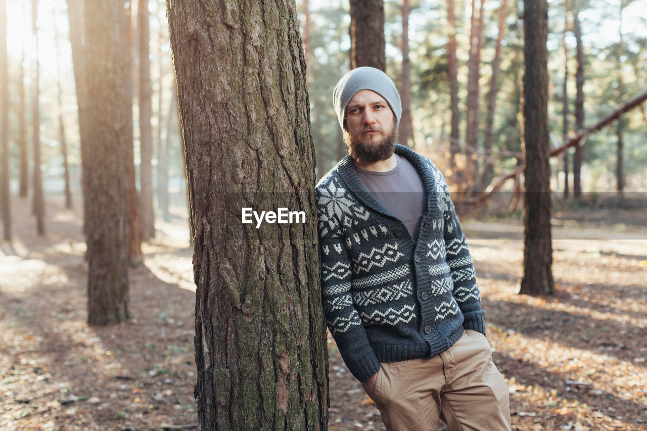 Thoughtful young man standing in forest