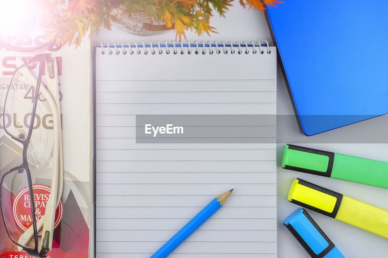 HIGH ANGLE VIEW OF PENCIL AND BOOK ON TABLE