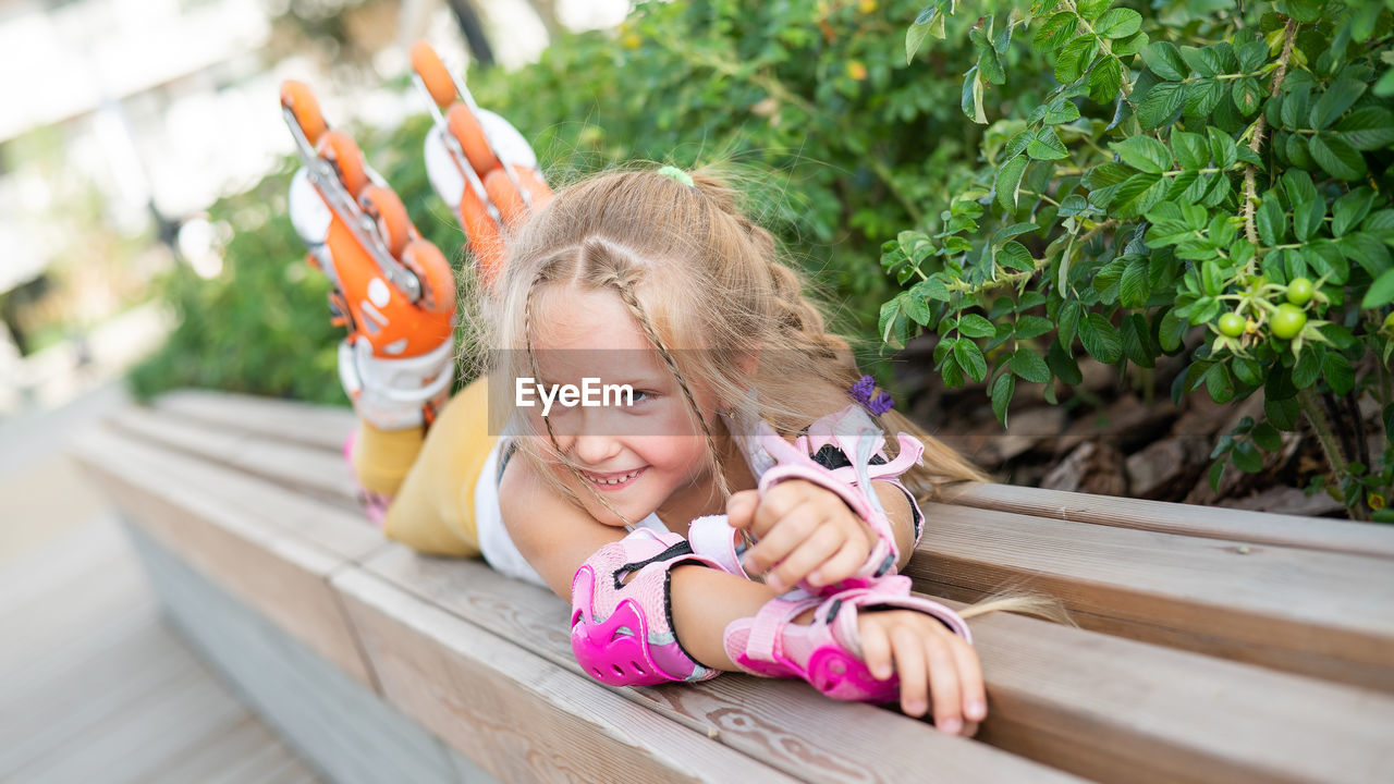 Smiling girl lying on bench outdoors