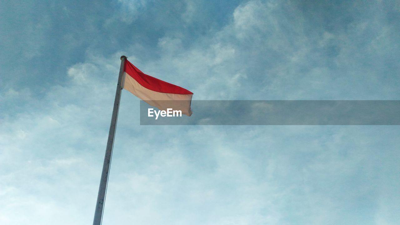 LOW ANGLE VIEW OF FLAGS AGAINST CLOUDY SKY