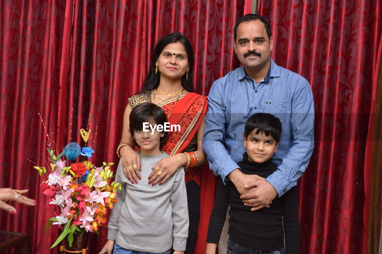 Portrait of happy family against curtain