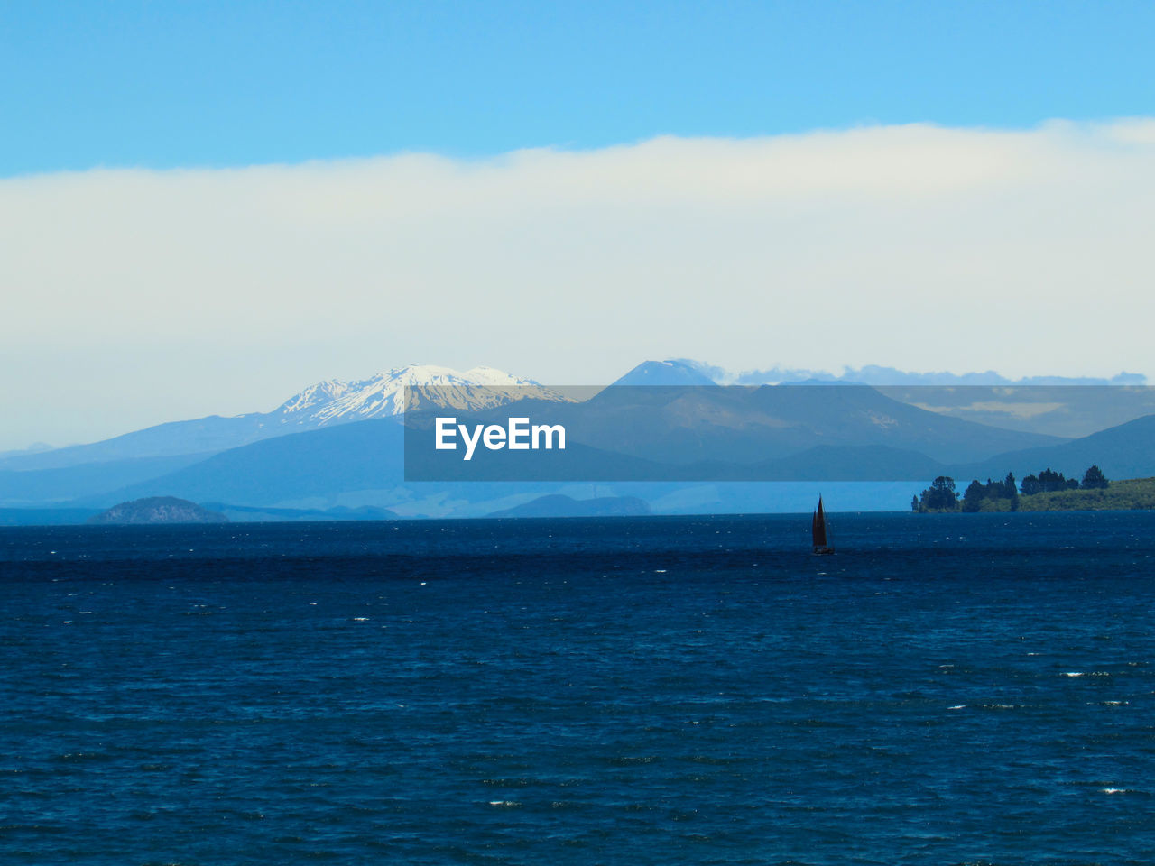 SCENIC VIEW OF SEA BY MOUNTAINS AGAINST BLUE SKY