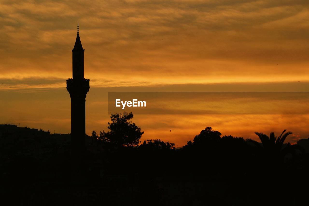 SILHOUETTE TREES AND BUILDING AGAINST ORANGE SKY