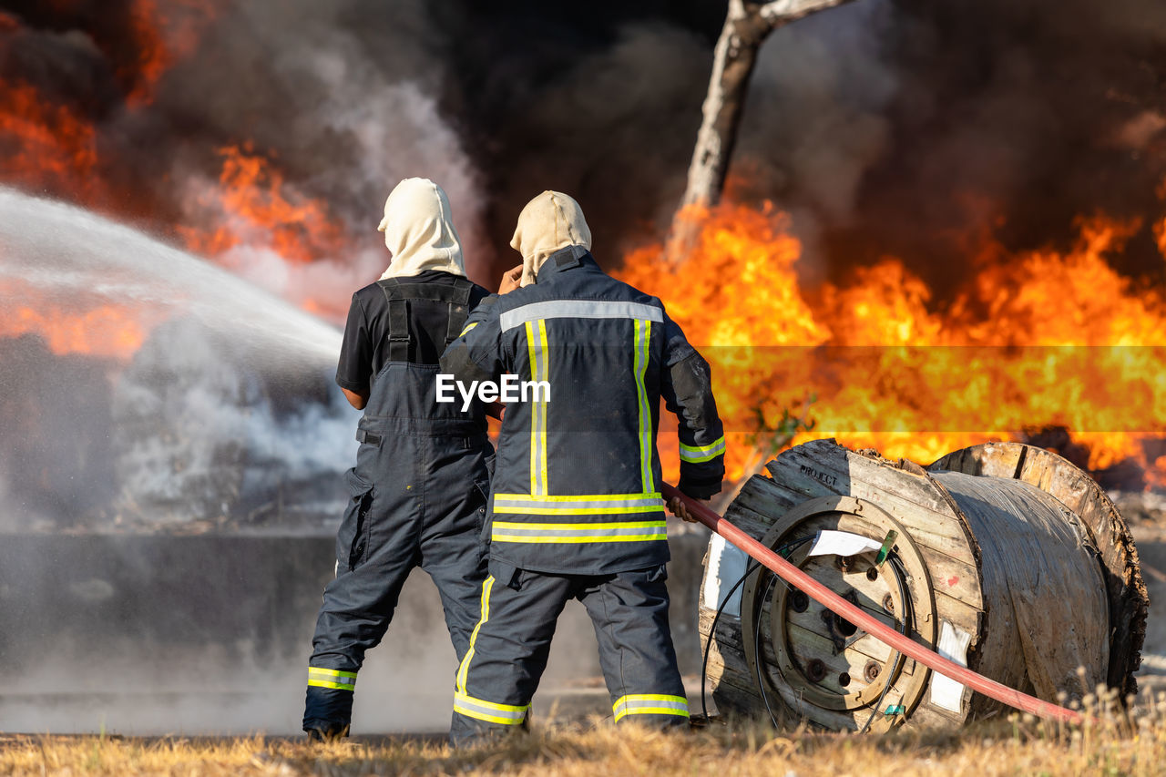 Fireman or firefighter spraying water from big water hose to prevent fire