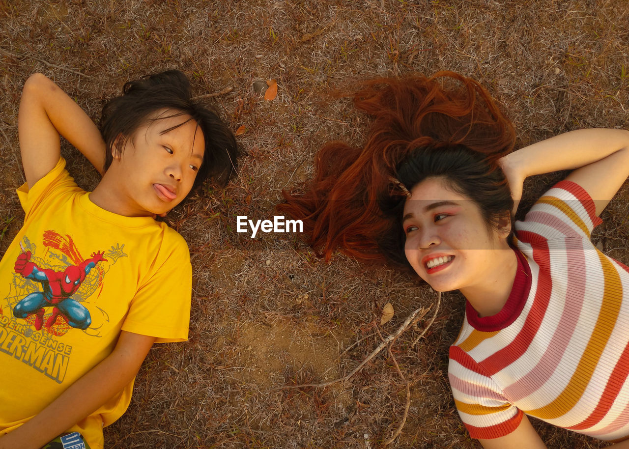 PORTRAIT OF A SMILING GIRL LYING DOWN ON FLOOR