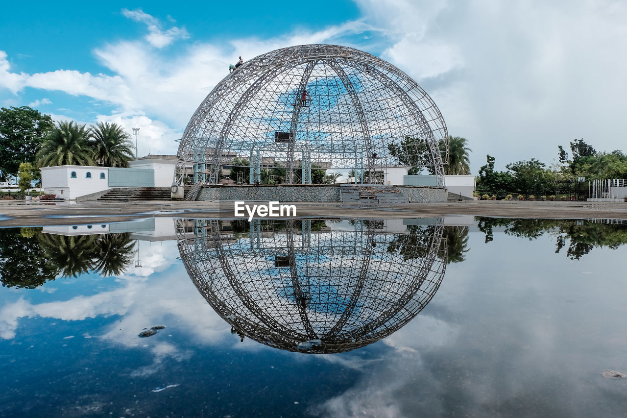 Reflection of spherical structure in river against sky