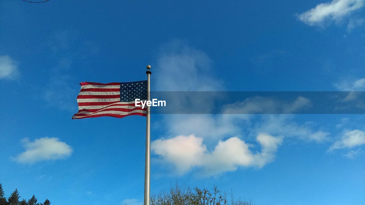 Low angle view of american flag against blue sky