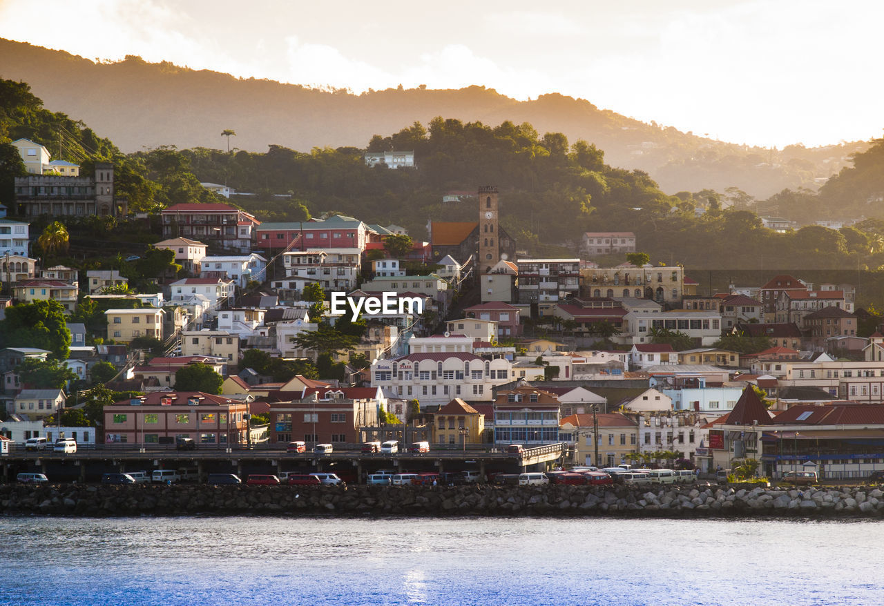 City by lake against clear sky during sunset