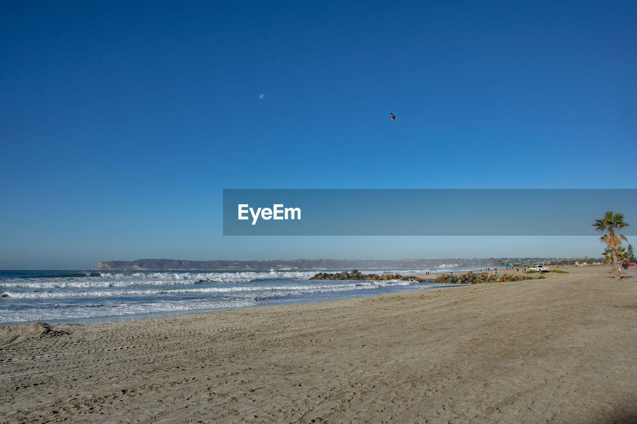 VIEW OF BEACH AGAINST BLUE SKY