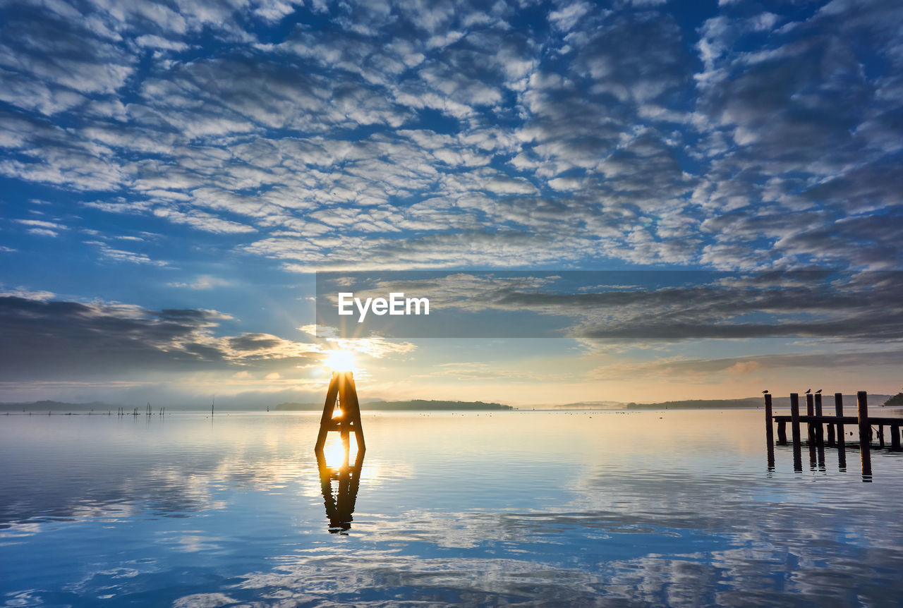 MAN ON SEA AGAINST SKY DURING SUNSET