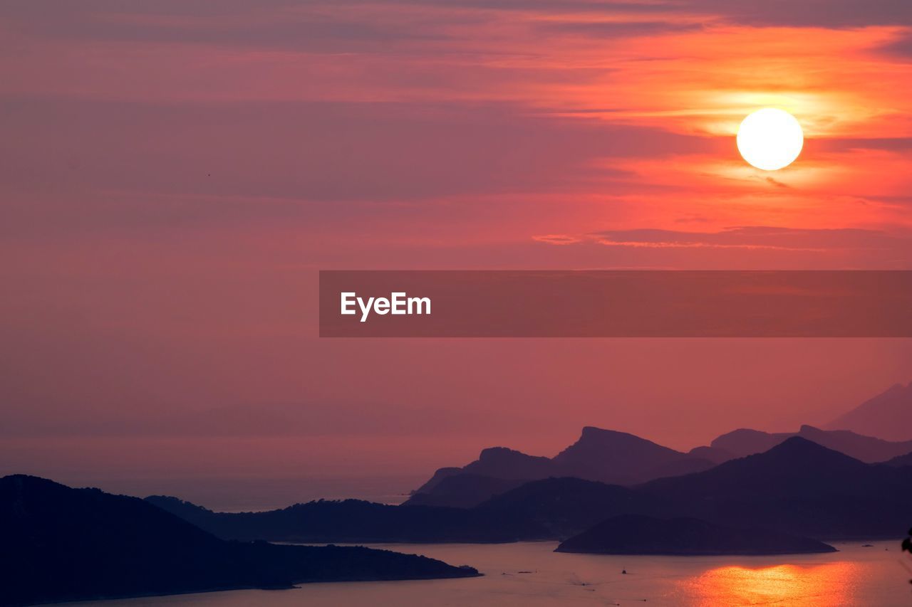 Scenic view of silhouette mountains against orange sky