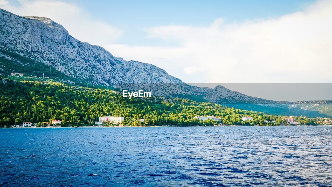 SCENIC VIEW OF CALM LAKE AGAINST MOUNTAIN RANGE