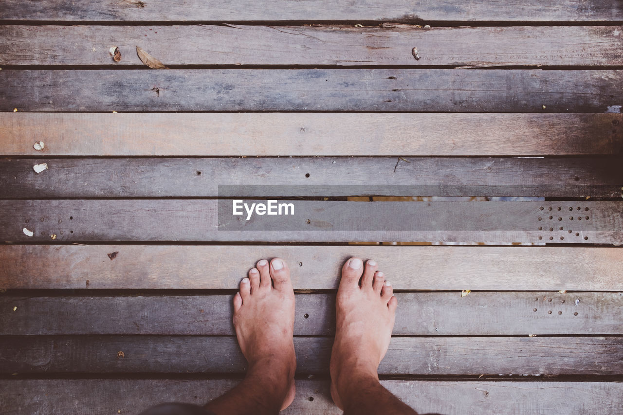 Low section of man standing on wooden footbridge