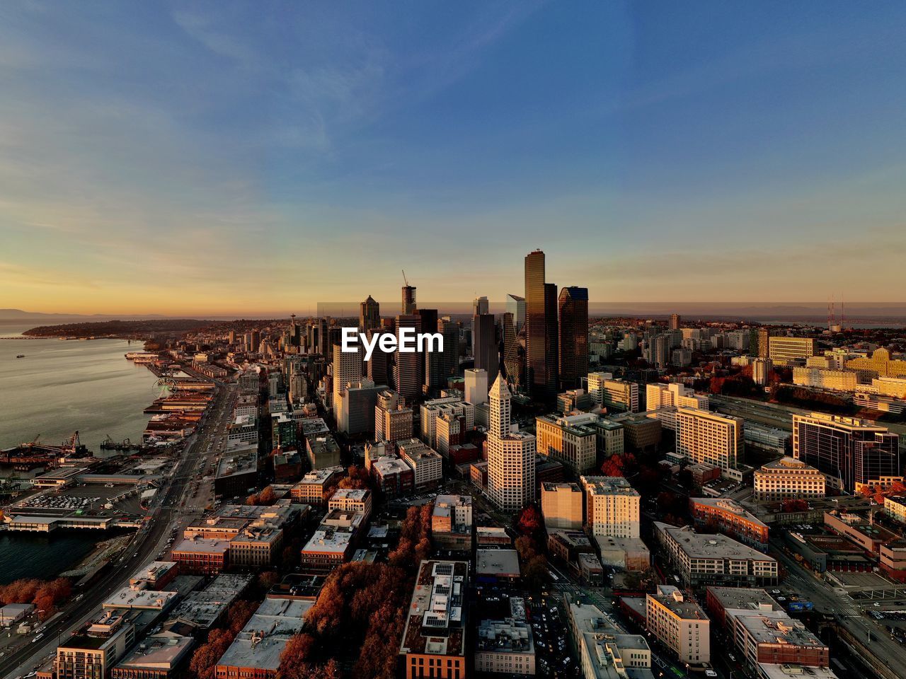 HIGH ANGLE VIEW OF MODERN CITY BUILDINGS AGAINST SKY DURING SUNSET