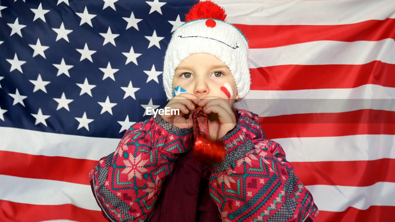 Close-up portrait of girl with party horn blower against american flag