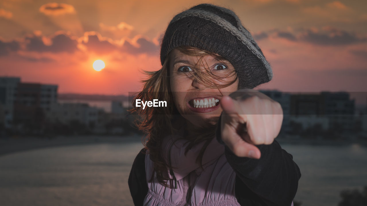 Portrait of angry woman standing against sky during sunset