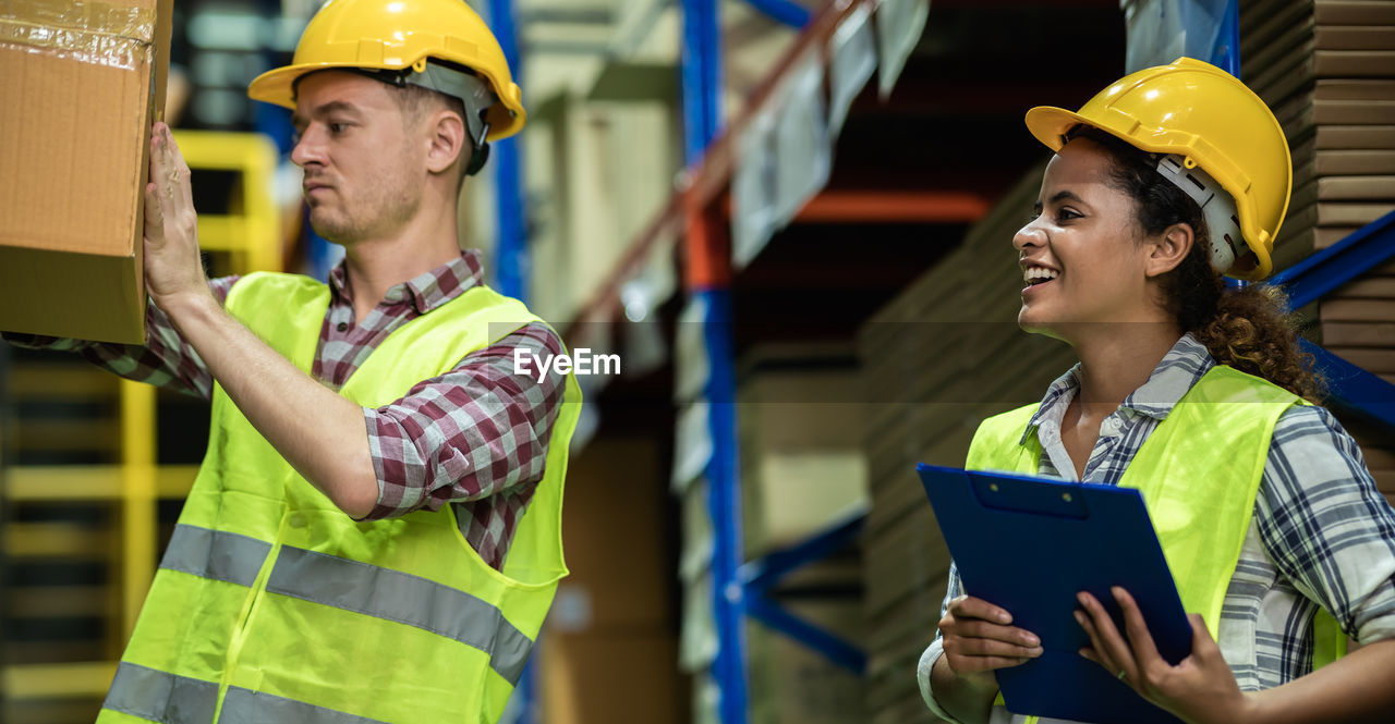 Multi ethnic warehouse worker working together in storage room. african woman working in warehouse.