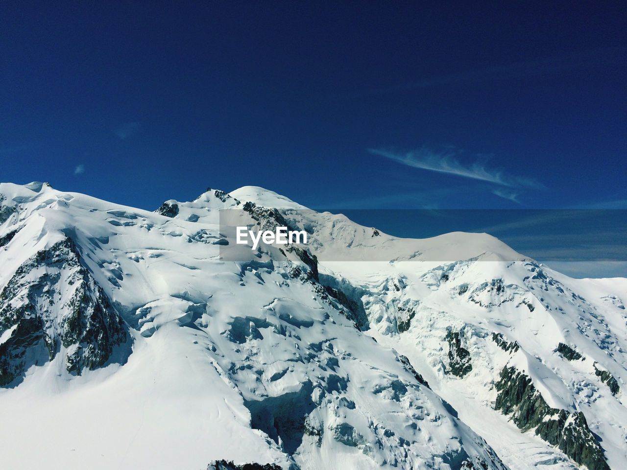 Scenic view of snowcapped mountains against blue sky