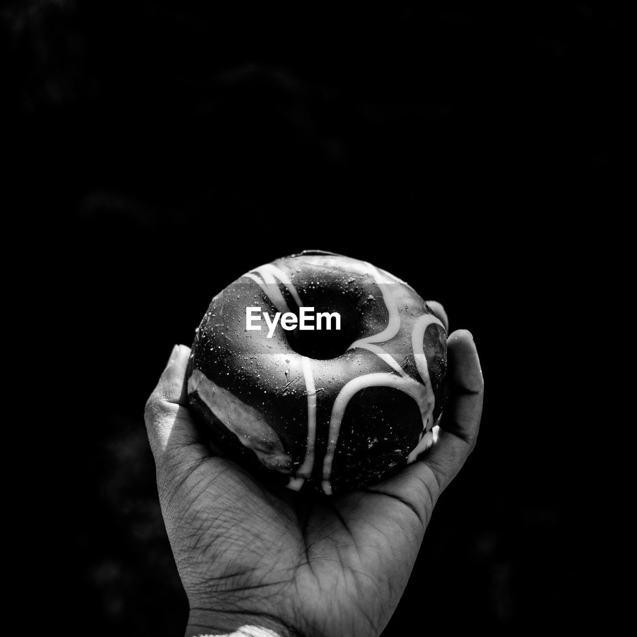 Cropped image of hand holding donut against wall