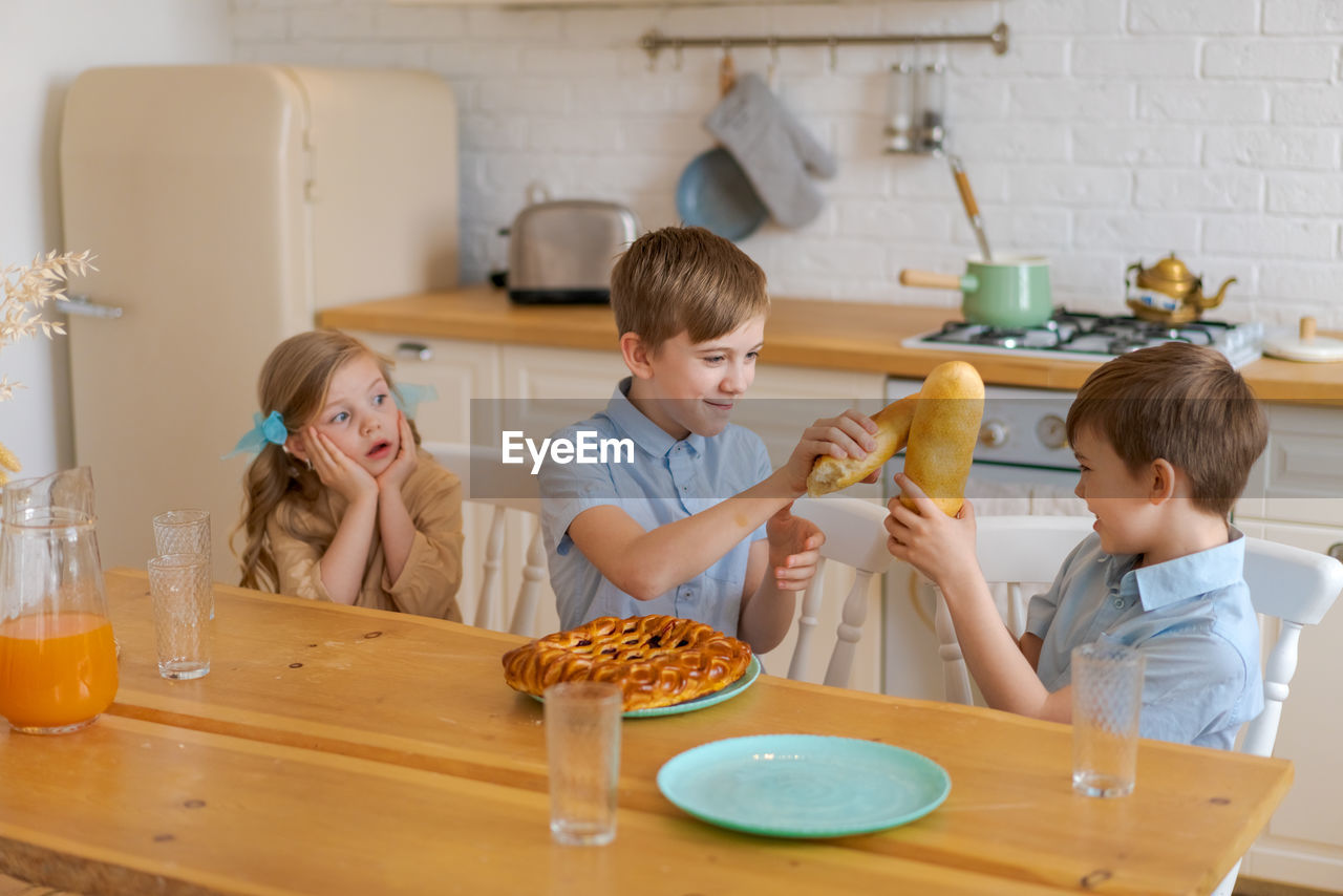 Caucasian mother sitting at table in kitchen children father serving preparing