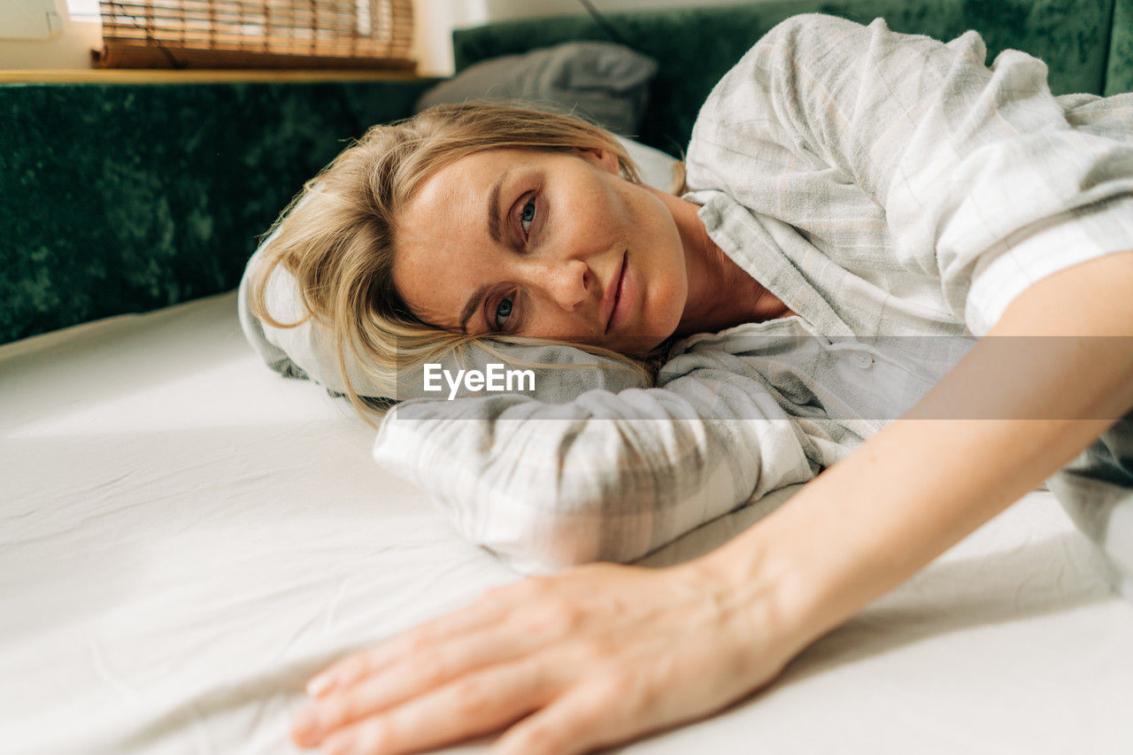 Portrait of a woman waking up early in the morning, lying on the bed.