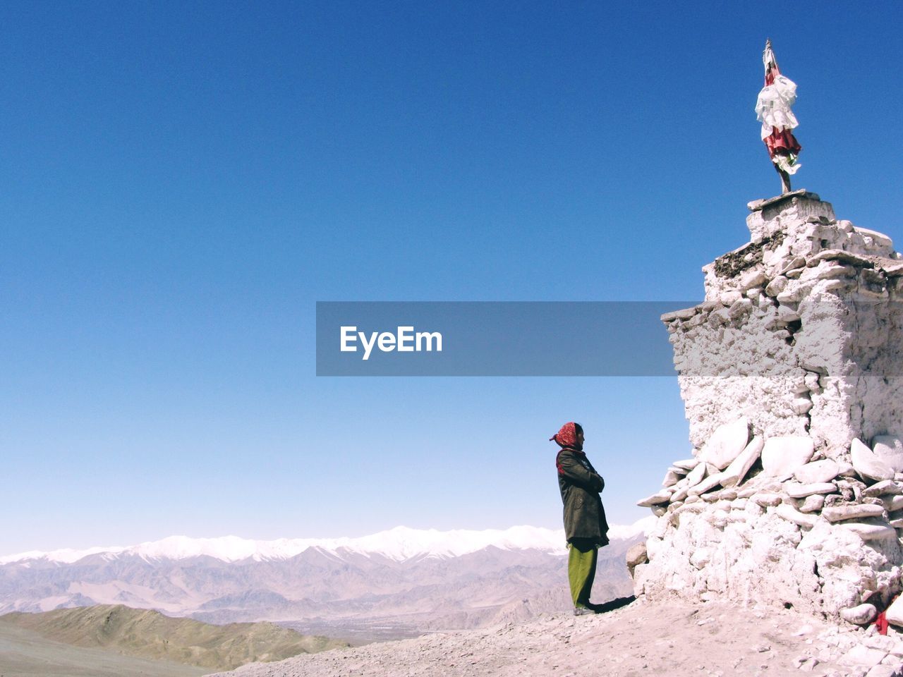 GIRL STANDING ON MOUNTAIN AGAINST CLEAR BLUE SKY