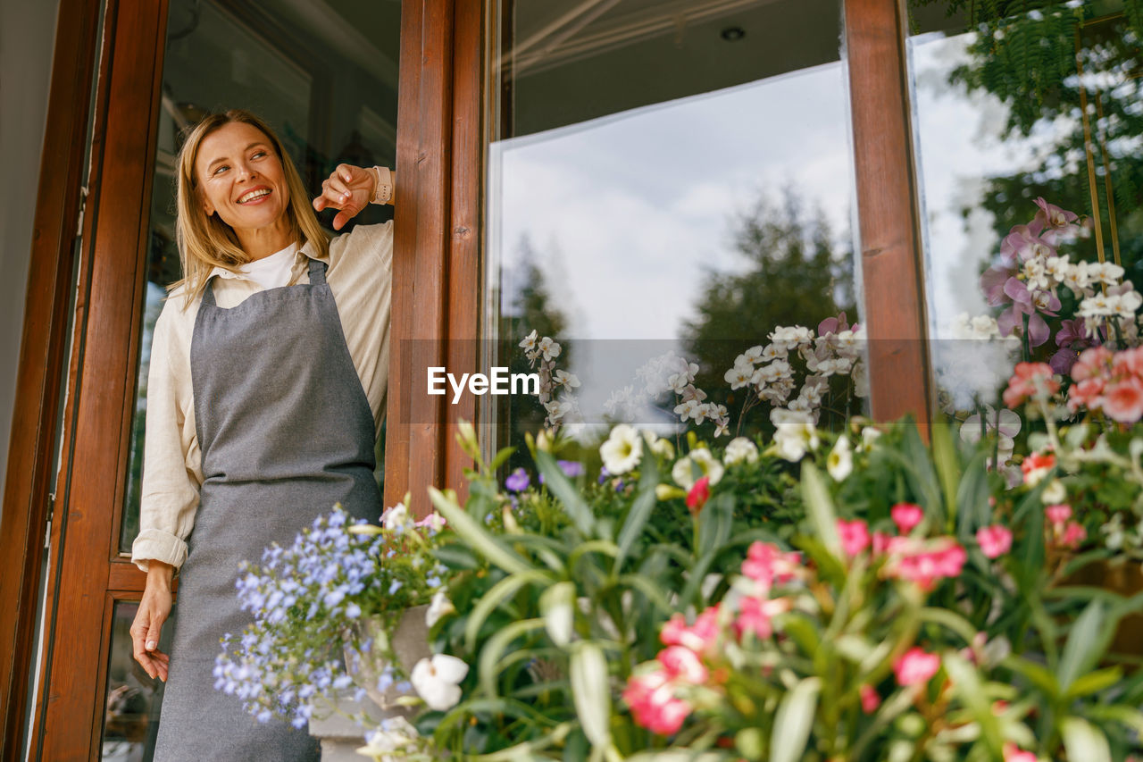 portrait of smiling young woman standing by plants