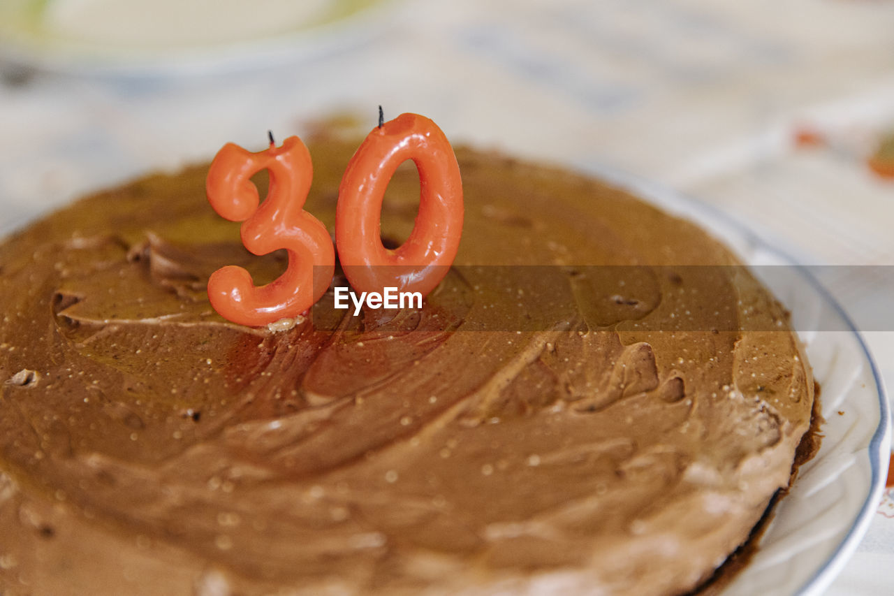 Delicious homemade birthday cake with candles in shape of 30 on table