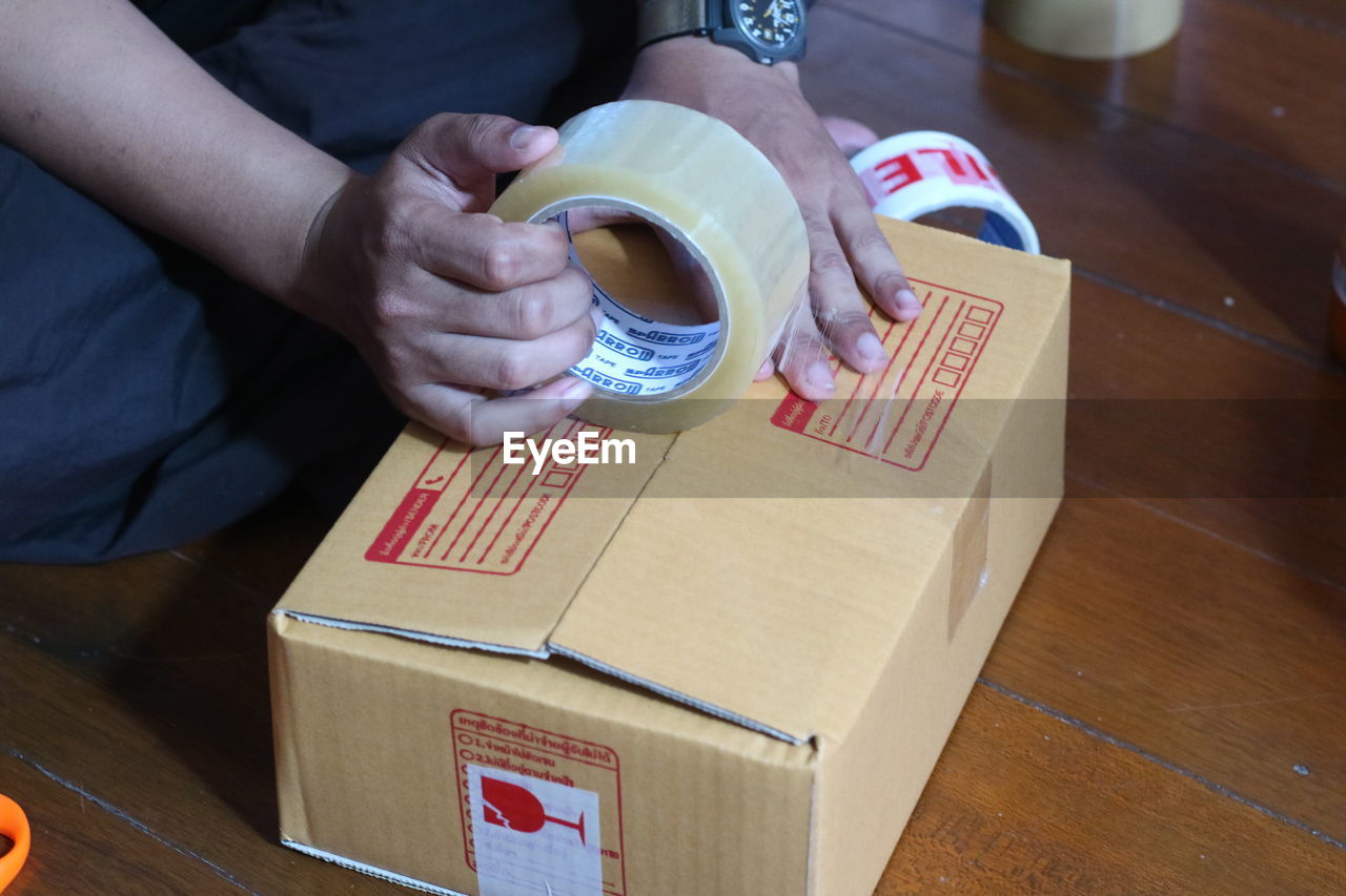 High angle view of man packing box on table
