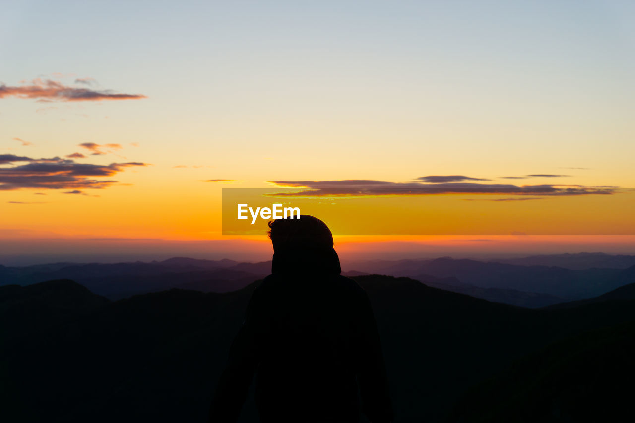 Silhouette man looking at mountain against sky during sunset