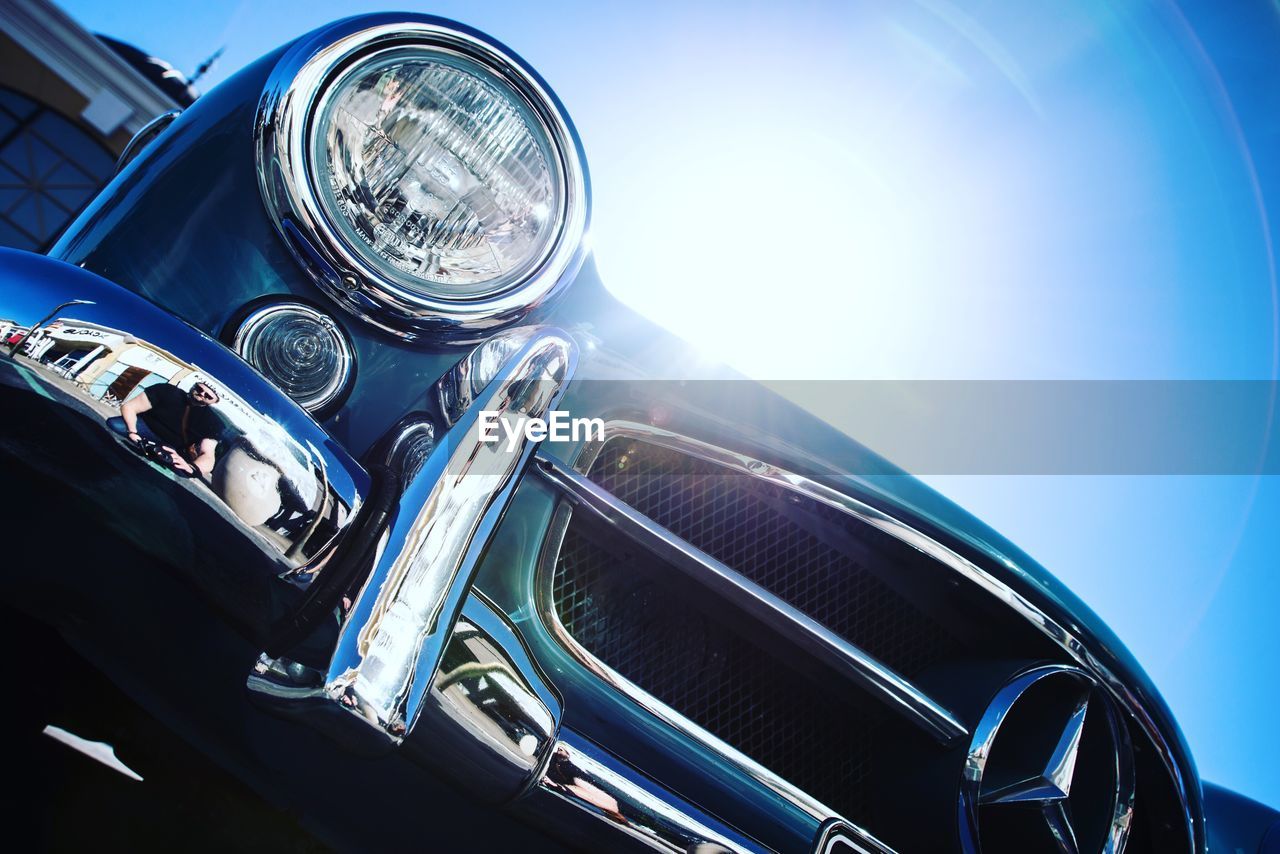 CLOSE-UP OF VINTAGE CAR ON BLUE ROAD