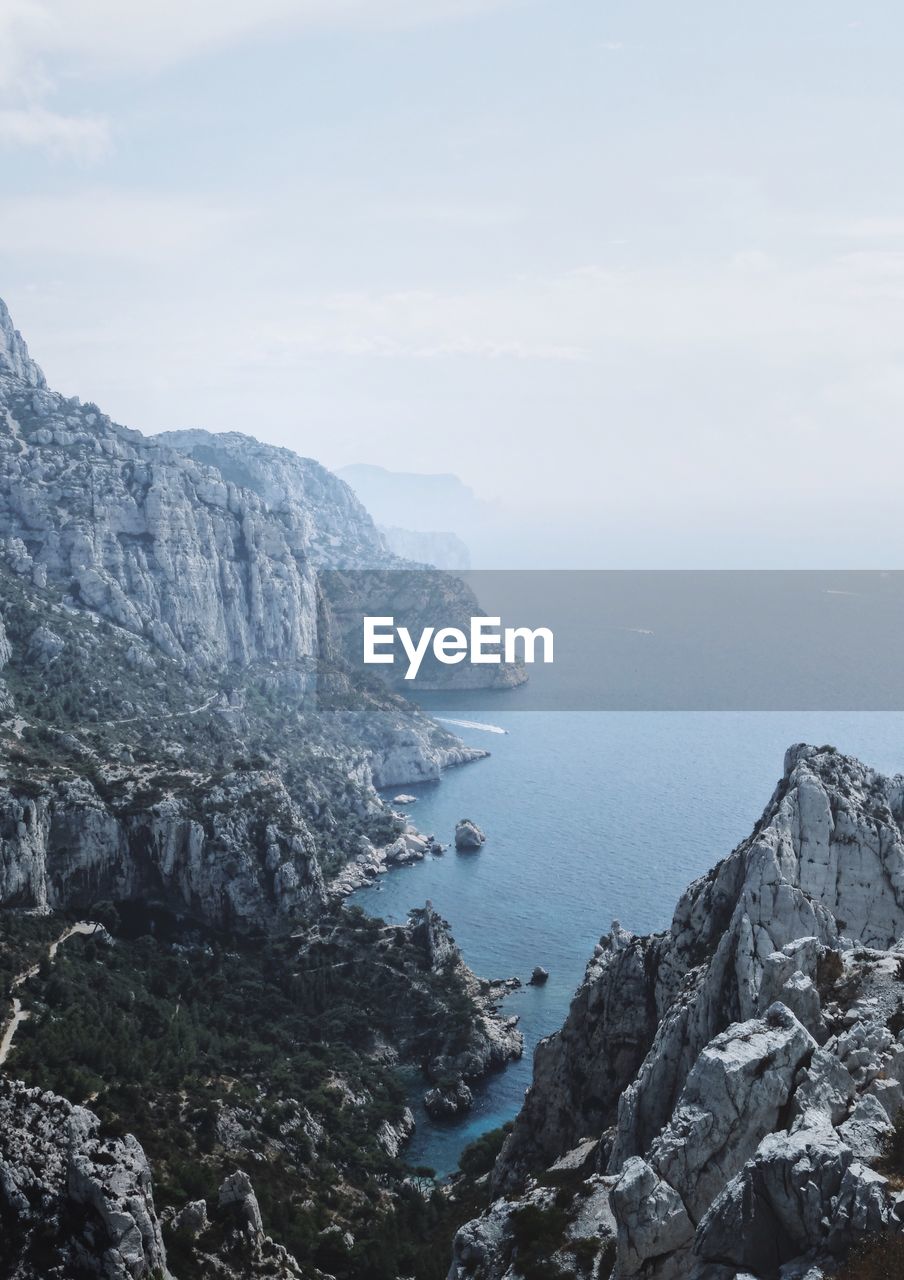 Scenic view of sea by mountains against sky