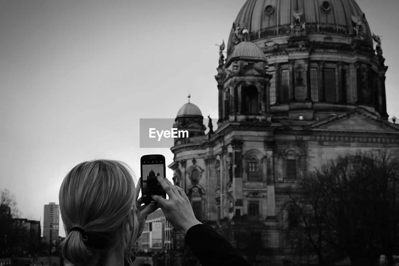 Rear view of woman photographing berlin cathedral in mobile phone