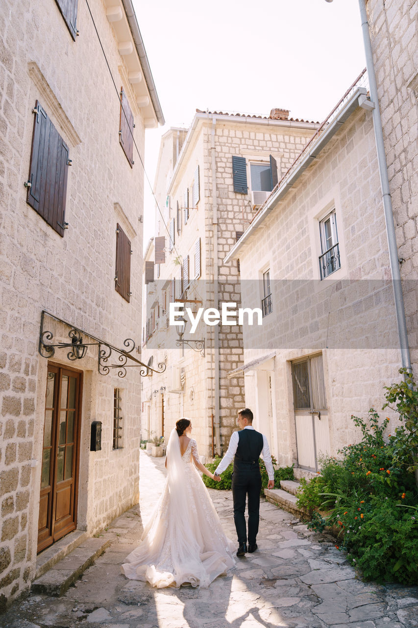 Rear view of couple walking on cobblestone street