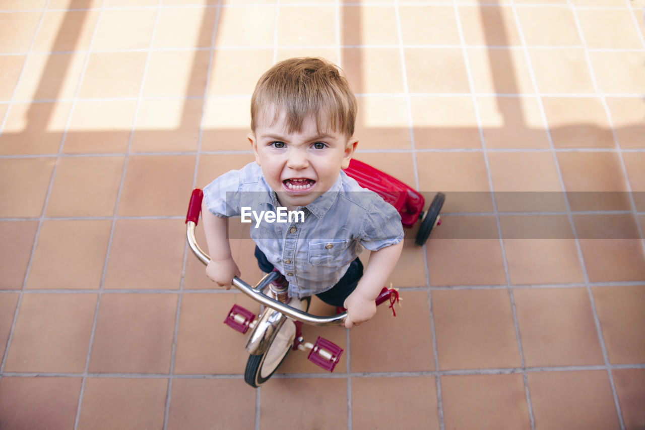 High angle portrait of boy riding bicycle on tiled floor
