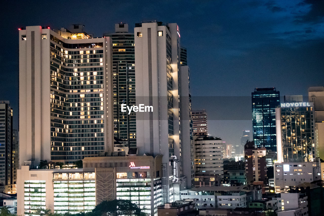 Illuminated buildings in city against sky at dusk