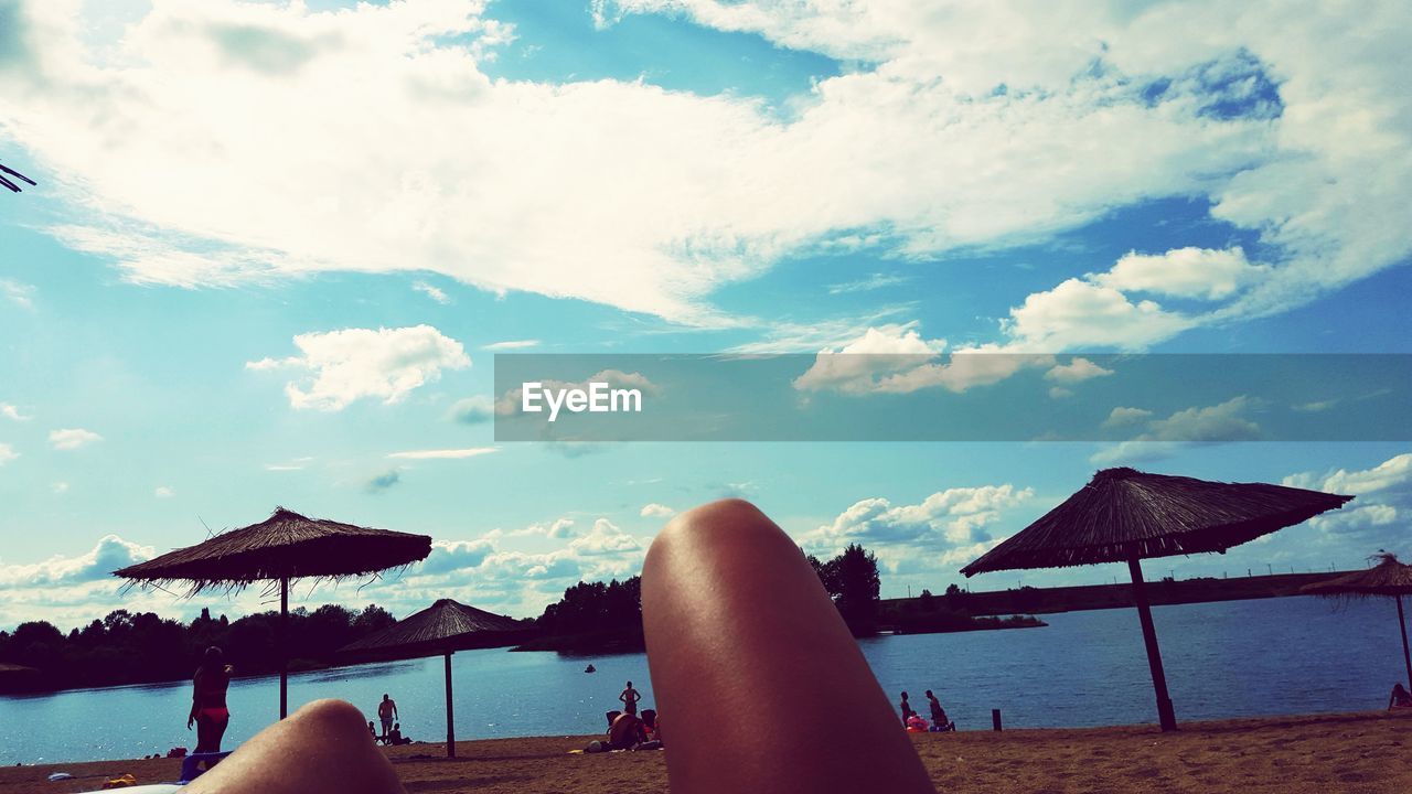 MAN RELAXING ON BEACH AGAINST SKY