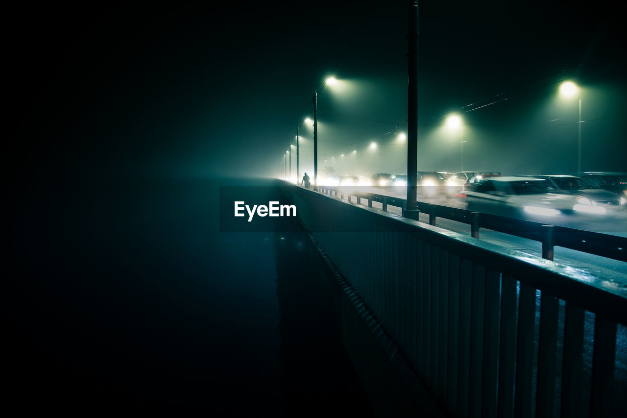 Illuminated bridge over river at night