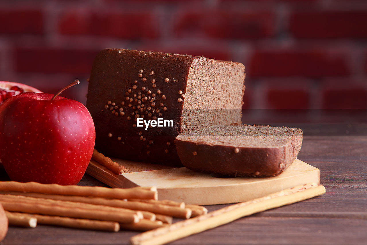 Different buns of fresh bread and spikelets of wheat on a brown vintage background