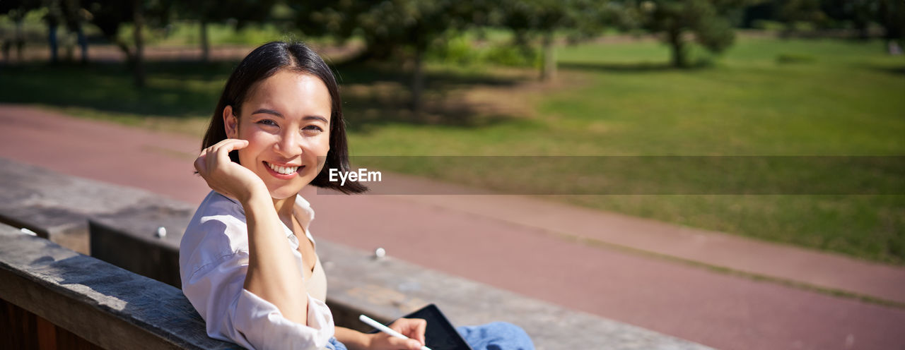 portrait of young woman using mobile phone while sitting outdoors