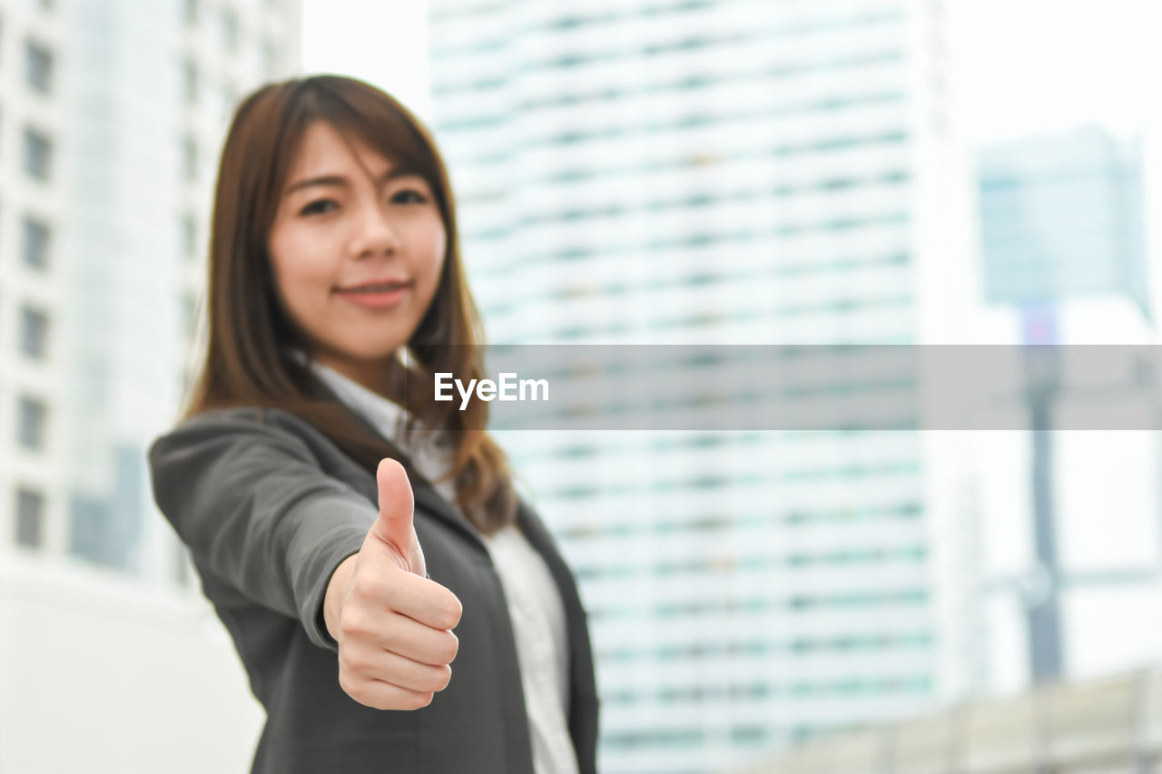 Young businesswoman gesturing while standing in city