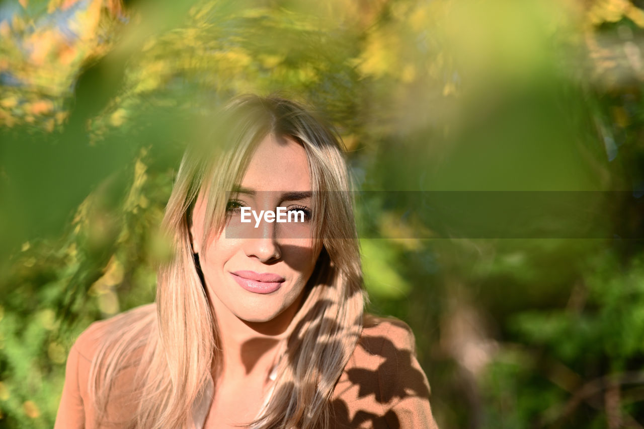 PORTRAIT OF SMILING YOUNG WOMAN WITH PLANTS