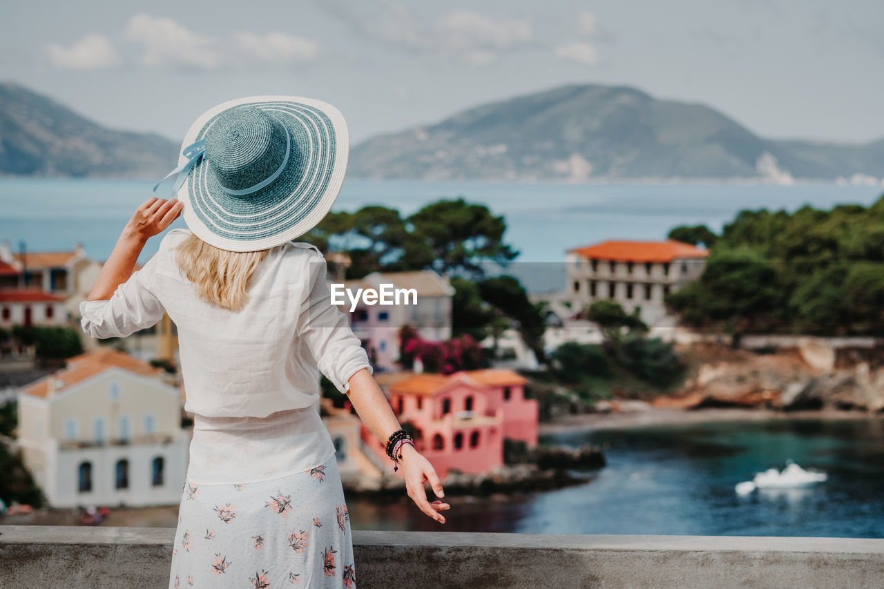 Rear view of woman looking at cityscape against sky