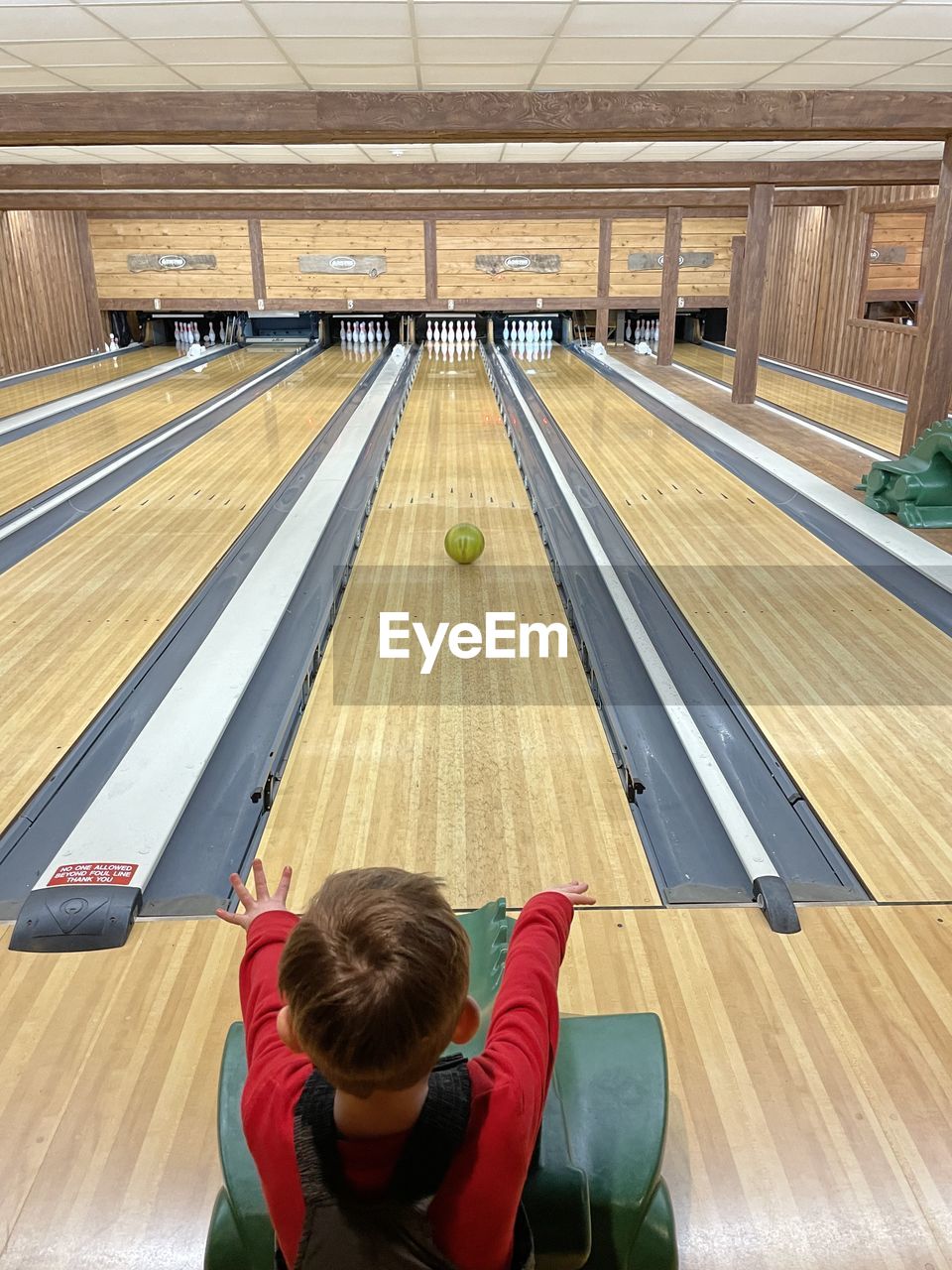 indoors, child, childhood, one person, bowling, floor, room, interior design, lifestyles, men, wood, architecture, women, looking, leisure activity, window covering, person, flooring, casual clothing, female, sports, adult