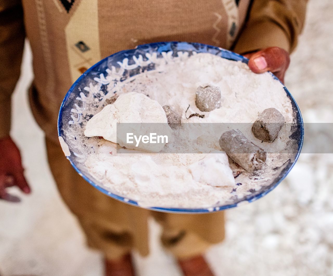 Midsection of worker holding minerals in plate