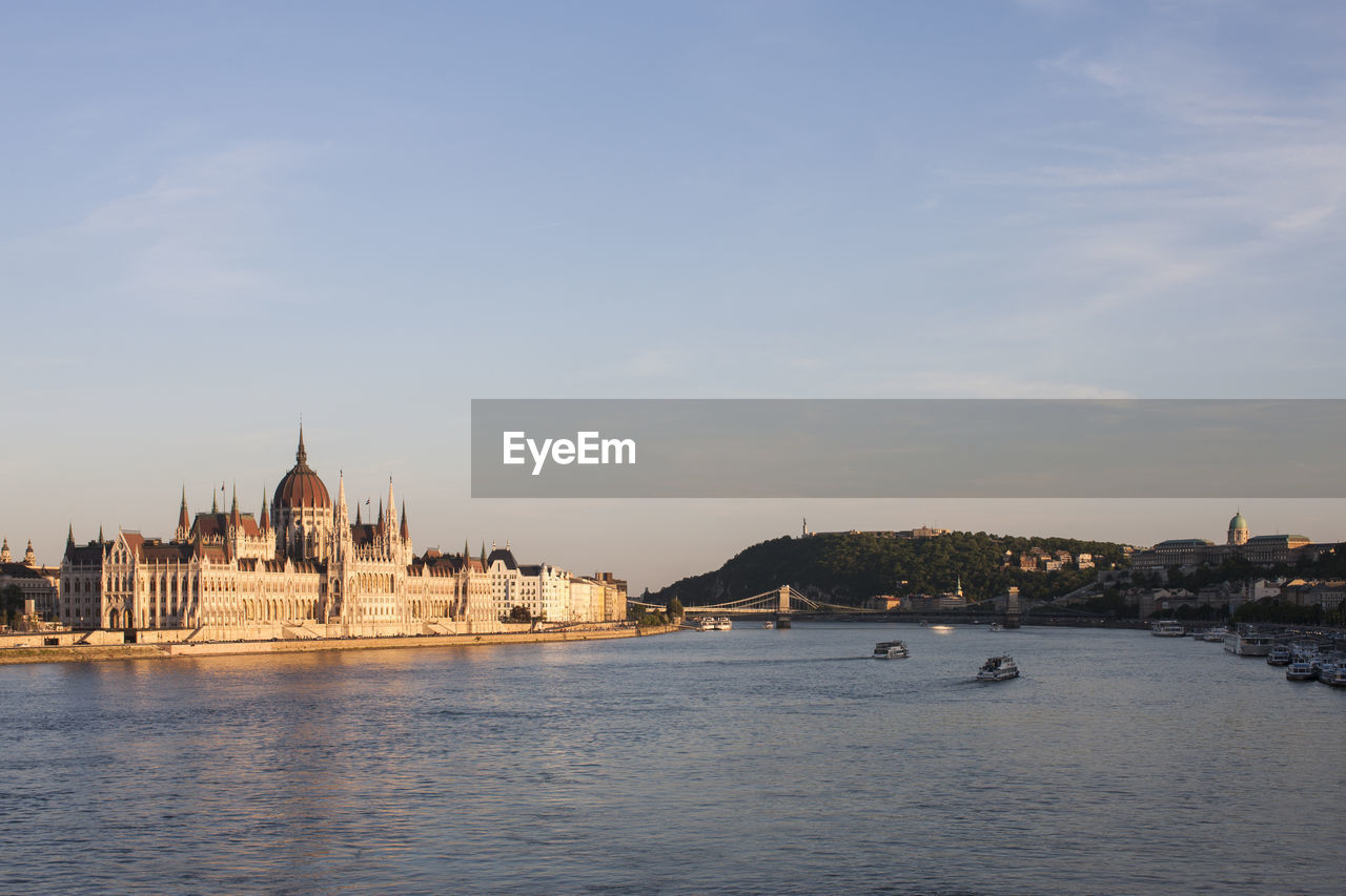 View of buildings by danube river against sky in budapest city