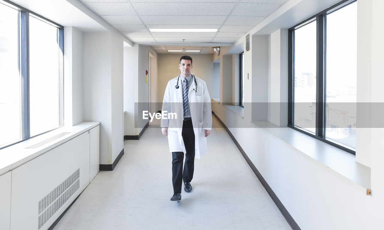 Doctor in white coat walking down the hallway in a hospital.