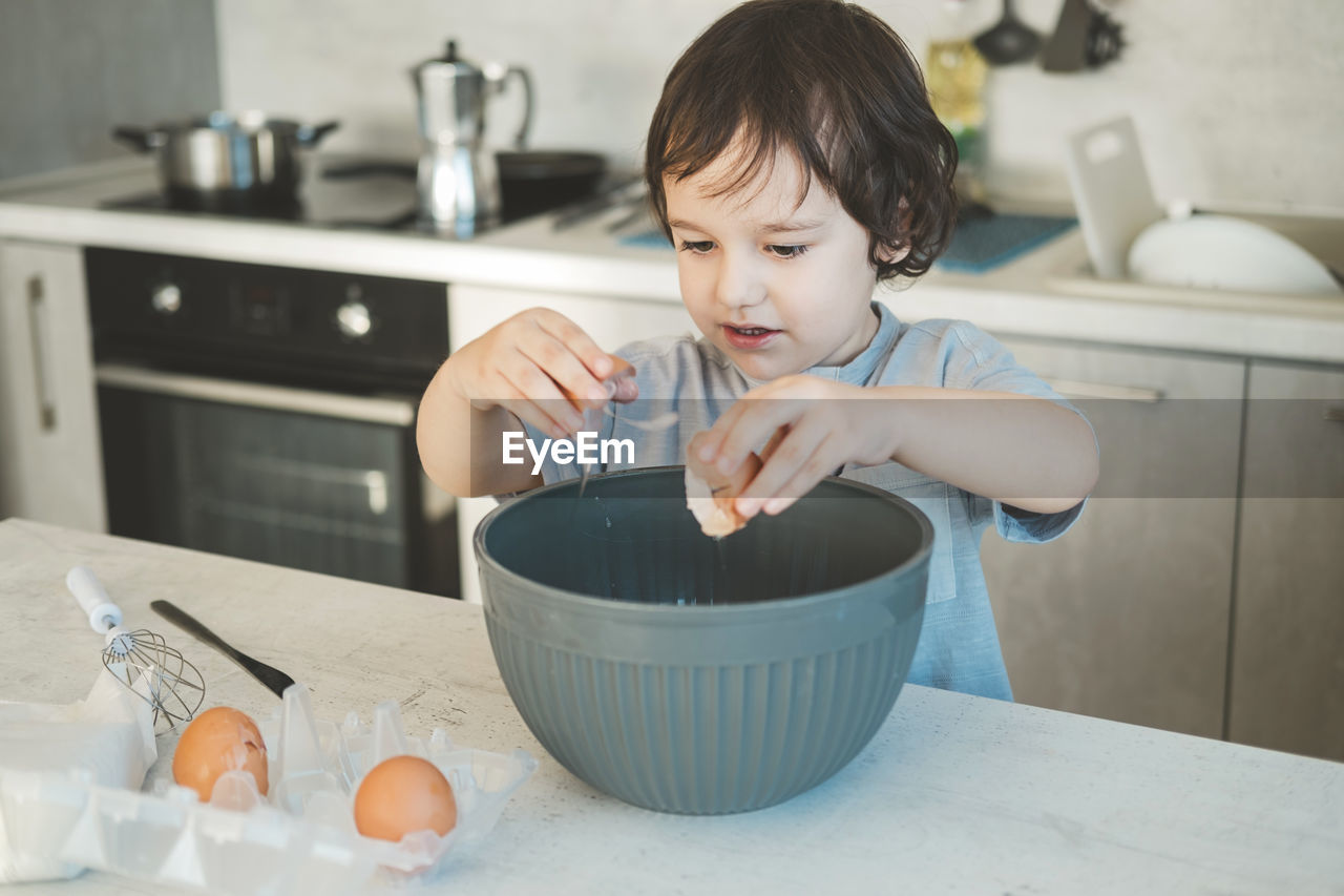 A little boy is cooking in the kitchen.