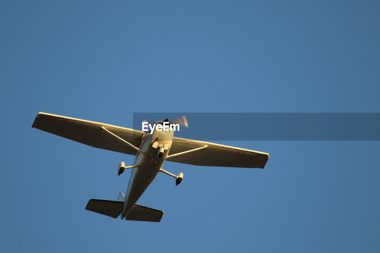 Low angle view of airplane against clear blue sky